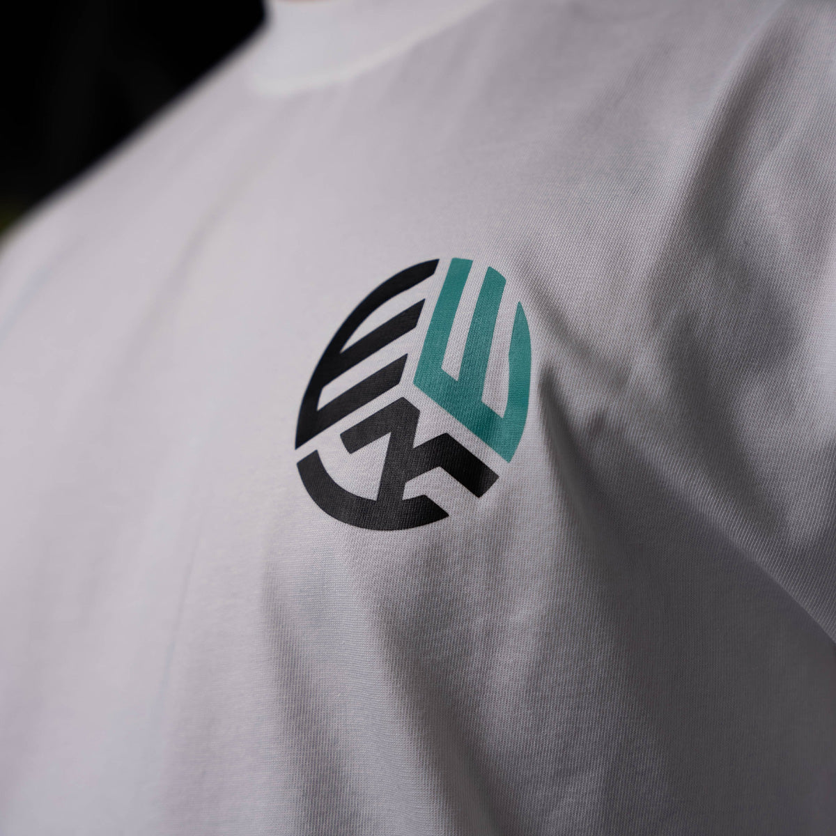 Close-up of EWK logo on white EWK Signature T-shirt