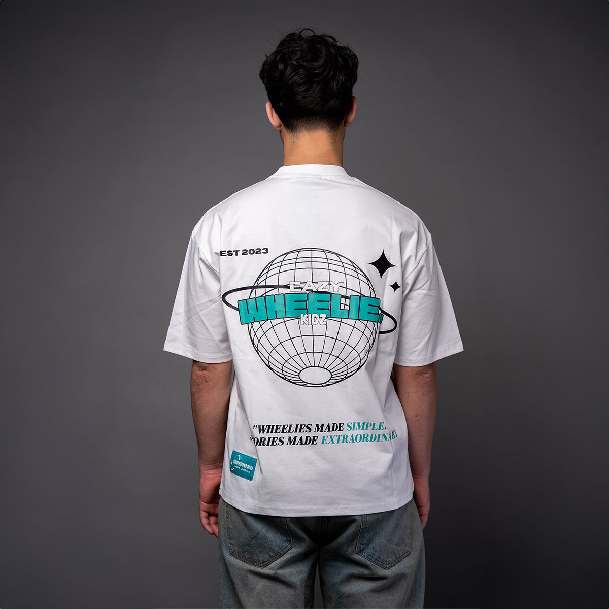 Back view of man wearing white EWK Signature T-shirt with teal Wheelie Kidz graphic